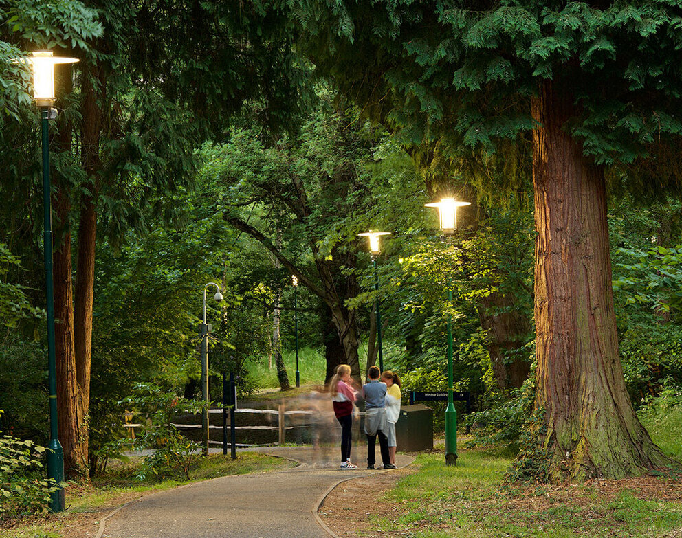 Sustainability. Compass of our actions. A group of people in a green park, illuminated by decorative SITECO luminaires.